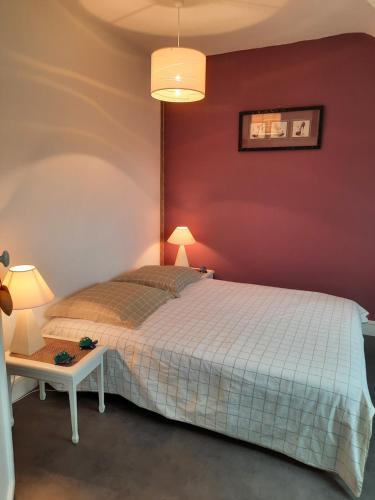 um quarto com uma cama branca e uma parede vermelha em Le Beau Verger em Le Mans