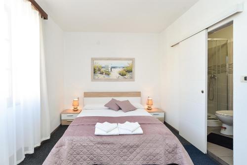 ein weißes Schlafzimmer mit einem Bett und einem Badezimmer in der Unterkunft Rooms Bale 2150 in Bale
