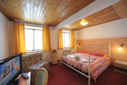 ein Schlafzimmer mit einem Bett, einem Sofa und einem TV in der Unterkunft Albergo Malga Ciapela in Rocca Pietore