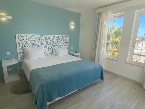 een slaapkamer met een bed met een blauw en wit hoofdeinde bij Mareta Beach - Boutique Bed & Breakfast in Sagres