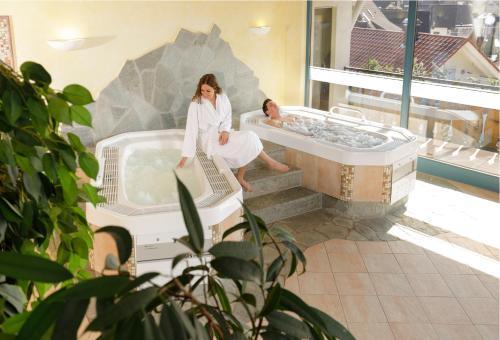 a woman sitting in a bath tub in a room at Hotel Rose in Baiersbronn