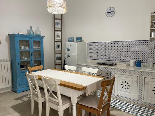 eine Küche mit einem Tisch und Stühlen sowie einem blauen Schrank in der Unterkunft B&B Vie del Mediterraneo in Porto Cesareo