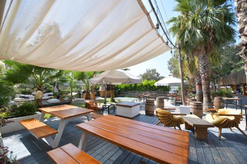 une terrasse avec des bancs, des tables et un grand parasol dans l'établissement No 22 Riders' Inn, à Akyaka