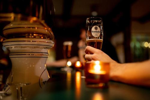 a person holding a glass of beer on a bar at Hotel Tiefenhagen Sauerland in Lennestadt