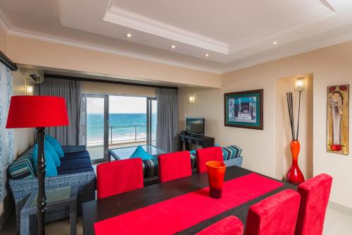 uma sala de estar com uma mesa vermelha e cadeiras vermelhas em Pebble Beach 26 em Ballito