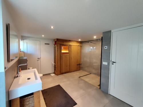 een badkamer met een wastafel en een douche bij Luxe vakantiehuis met sauna De Barn Bergen in Bergen