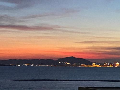 a sunset over the water with a city and mountains at 舊事民宿 Old things in quemoy in Hu-hsia