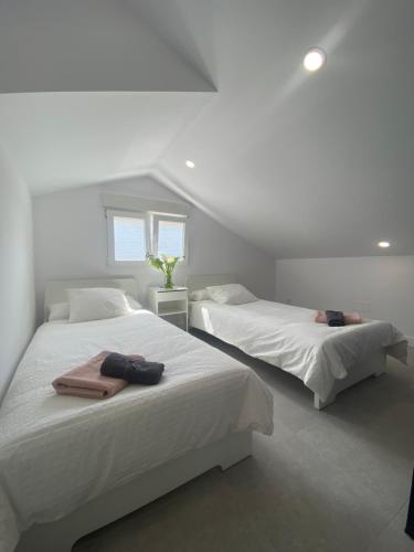 two beds in a bedroom with white walls at Design Club Santander in Santander