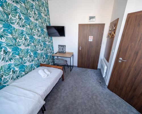 a small room with a bed and a small desk at Kelman Inn Global Nowa Sól in Nowa Sól