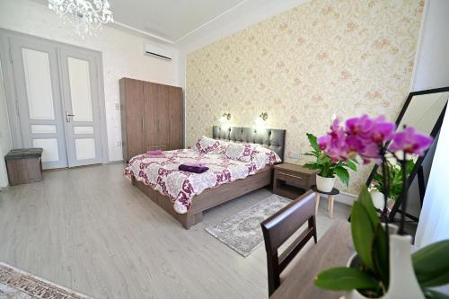 1 dormitorio con 1 cama, mesa y flores en FLH - Royal Studios, en Sibiu