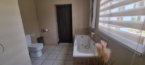a bathroom with a toilet and a tub and a sink at Heimat Guesthouse in Welkom
