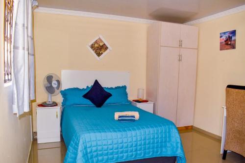 a bedroom with a blue bed with a blue blanket at Gabade Guest House in KwaDukuza