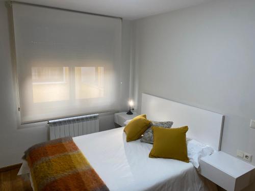 um quarto com uma cama com almofadas amarelas e uma janela em O SECRETO em Padrón