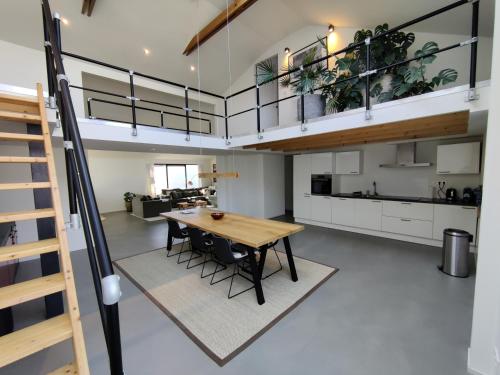 a kitchen and living room with a table and a loft at Luxe vakantiehuis met sauna De Barn Bergen in Bergen