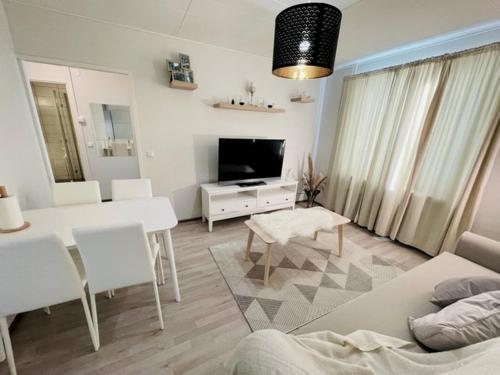 een woonkamer met een tafel en een woonkamer met een televisie bij Ilona Apartments - "The City Condo" in Kotka