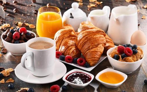 a table with a breakfast of croissants and coffee and fruit at Alepou Guest House in Gasperina