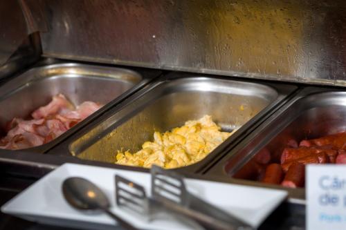 a counter with two trays of food in a kitchen at Hotel CH Bucharest in Bucharest