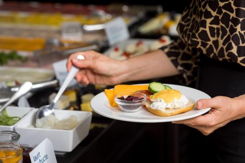a person holding a plate of food on a counter at Hotel CH Bucharest in Bucharest
