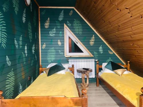 two beds in a room with a green wall at Karczma Leśniczanka in Wielbark