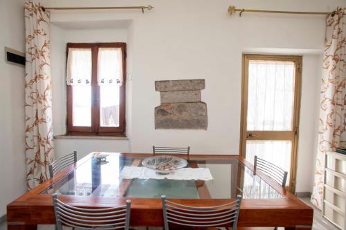 uma sala de jantar com uma mesa de vidro e cadeiras em Sulla Valle di Seccheto em Seccheto