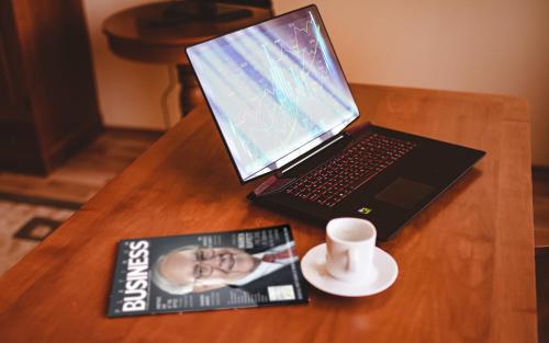 a laptop computer on a table with a book and a cup of coffee at Septimia Hotels & Spa Resort in Odorheiu Secuiesc