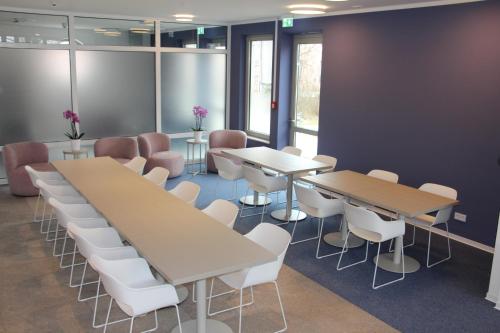 a conference room with two tables and white chairs at SCOTTY & PAUL Hotel Deggendorf in Deggendorf