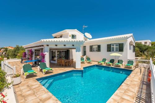 a villa with a swimming pool in front of a house at Villa Marisol in Sant Lluis