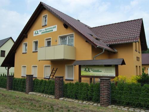 una casa amarilla con un cartel delante en Pension + Apartments Tor zum Spreewald, en Lübben