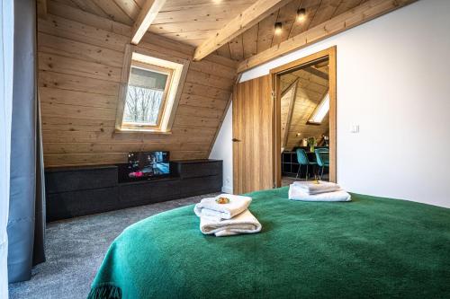 a bedroom with a green bed with towels on it at Willa Trawers in Zakopane
