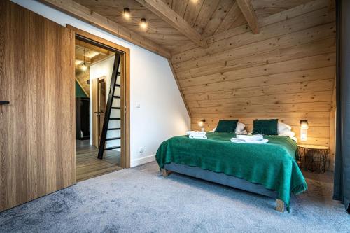 a bedroom in a wooden house with a green bed at Willa Trawers in Zakopane