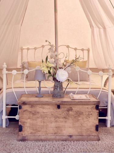 a bed with a vase of flowers on a wooden table at Valley Farm Bells in Oxford