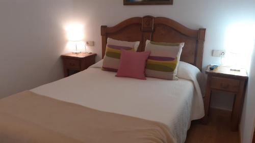 a bedroom with a white bed with pillows and two lamps at Apartamentos El Haya in Cosgaya