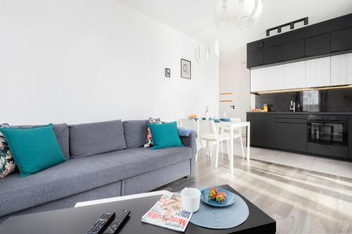 a living room with a gray couch and a kitchen at Deluxe Apartments Sucha Gdańsk by Renters in Gdańsk