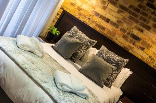 a bedroom with a bed with pillows and a brick wall at Grey Manor Guesthouse in Potchefstroom