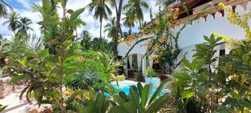 a garden with a swimming pool and palm trees at MOYO apartment in Pwani Mchangani