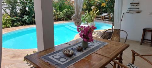 a table with flowers on it next to a swimming pool at MOYO apartment in Pwani Mchangani
