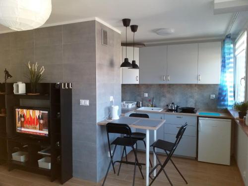 uma cozinha com mesa e cadeiras e uma televisão em Apartament Centrum 32m2 Kłodzko - Przyjaciół Ziemi Kłodzkiej em Kłodzko