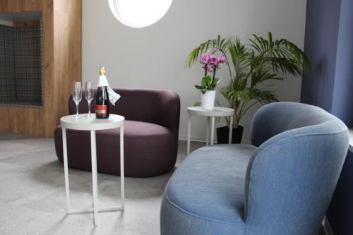 a living room with a chair and two tables with wine bottles at SCOTTY & PAUL Hotel Deggendorf in Deggendorf