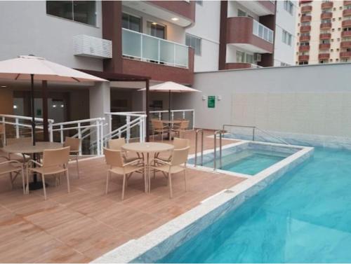 a patio with tables and chairs next to a swimming pool at Apartamento tipo Flat para temporada em Caldas Novas com cozinha in Caldas Novas