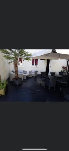 a room with tables and chairs and a palm tree at HÔTEL RESTAURANT LE PICARDIE in Chauny