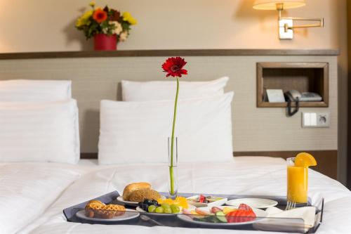 a tray with a plate of food on a bed at Hotel CH Bucharest in Bucharest