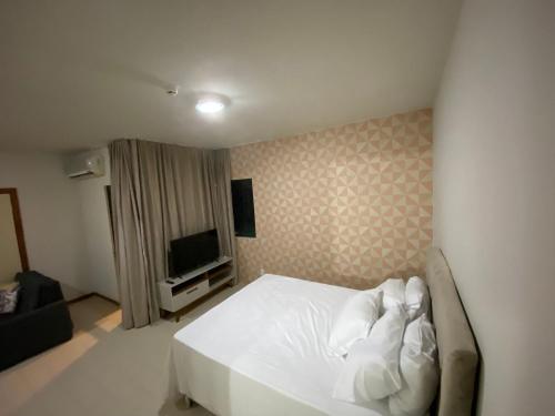 1 dormitorio con 1 cama blanca y TV en Lindo Flat Hotel Costa Mar en Recife