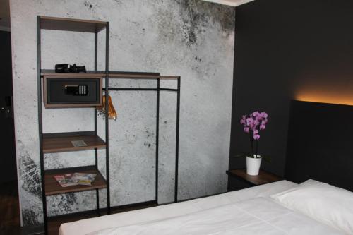 a bedroom with a bed and a shelf with a microwave at SCOTTY & PAUL Hotel Deggendorf in Deggendorf