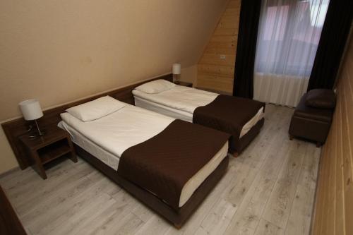 two beds in a small room with a chair at BAYKA - SPA resort in Kosiv