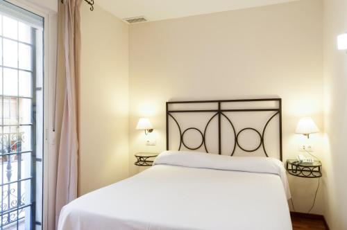 Un dormitorio blanco con una cama grande y una ventana en Apartamentos Murillo, en Sevilla