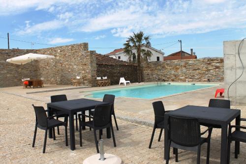 a patio with tables and chairs next to a swimming pool at Casal da Porta - Quinta da Porta in Mirandela