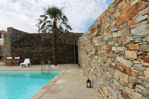 a stone wall next to a swimming pool at Casal da Porta - Quinta da Porta in Mirandela
