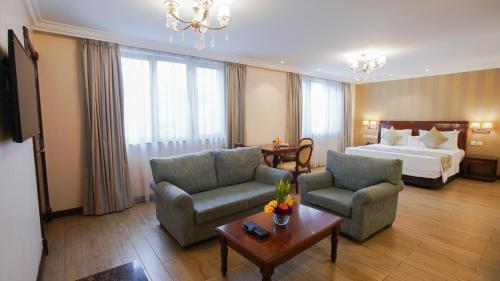 a hotel room with a bed and two chairs and a table at Sarova Woodlands Hotel and Spa in Nakuru