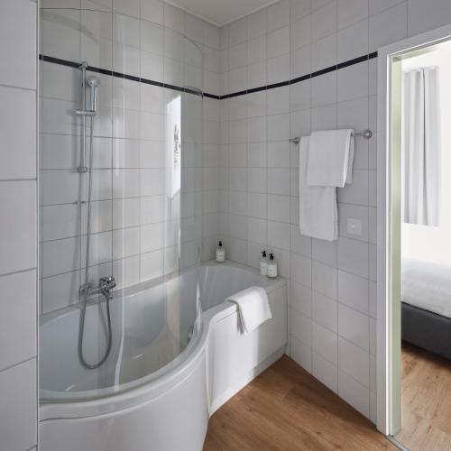 a white bathroom with a tub and a shower at Base Lausanne in Lausanne