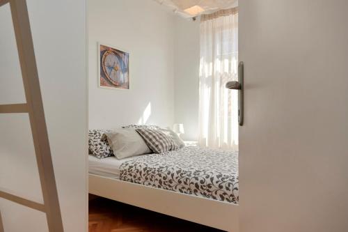 a white bedroom with a bed and a window at Apartment Tin in Trogir